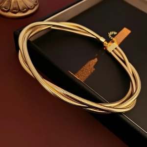 Vue macro d'un collier chaîne serpent dorée multicouche dans un écrin cadeau noir chic