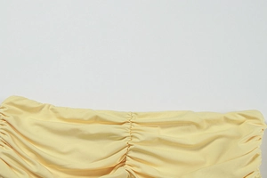 Detailed macro view of pale yellow ruched fabric and fine pleated stitching on the dress