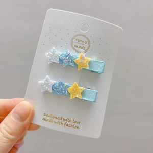 Pair of light blue glitter star hair clips for girls on a handmade display card