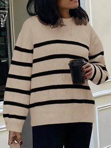 Street style view of women's loose fit striped knit sweater with crew neck and long sleeves