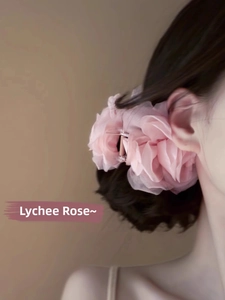 Elegante pinza per capelli con grande fiore rosa in tessuto indossata da una modella