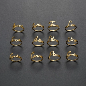 Set of 12 golden stainless steel zodiac rings featuring nameplate engravings on dark background