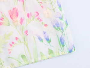 Detail of floral embroidery and pink purple flower patterns on white summer dress