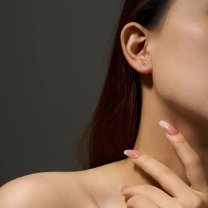 Close-up of 925 silver stud earrings with iridescent opal stones on a model's ear