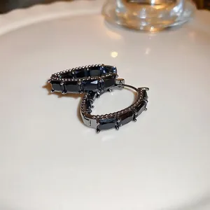 Boucles d'oreilles créoles en argent et zircon noir sur un plateau en céramique