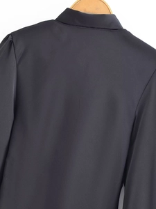 Detail of black long-sleeve blouse featuring puff shoulder design on a wooden hanger