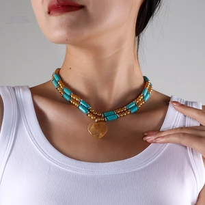 Detailed close-up of double-layered turquoise bead necklace with amber heart pendant