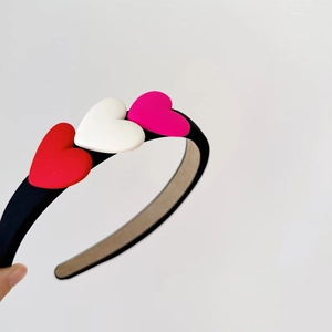 Detail of sweet heart headband with red white and pink 3D hearts on a black band