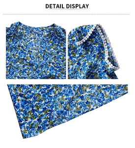 Detailed view of blue floral print V-neckline and white lace ball trim on sleeve