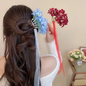 Detail of elegant fabric flower hairpins with long ribbon tassels on a bun hairstyle