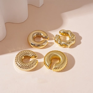 Close-up of four assorted gold-plated ear cuffs with twisted and textured C-shape designs