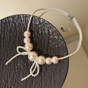 Detail of bow-shaped pearl pendant necklace with adjustable silver lobster clasp