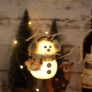 Illuminated knitted snowman ornament with plaid scarf hanging on a white branch