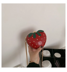 Close-up of strawberry heart bag with golden studs and metal chain strap