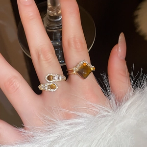 Detail of gold snake rings with tiger eye stones and pearls on white fur cuff