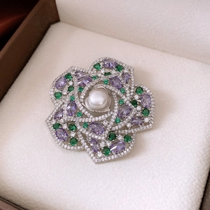 Macro view of floral brooch with white pearl, purple gemstones and zircon inlay