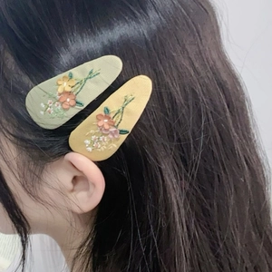 Floral embroidered fabric BB hair clips in light green and yellow on dark hair