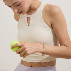 Detail of gold zircon bracelet on wrist with a tennis ball for a sporty luxury look