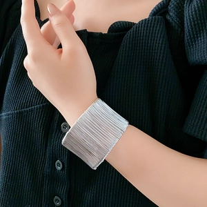 Dettaglio di un bracciale a fascia in argento multistrato su modella con sfondo nero