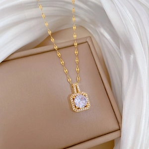 Makroaufnahme des goldenen quadratischen Anhängers mit Zirkonia auf Seidenstoff