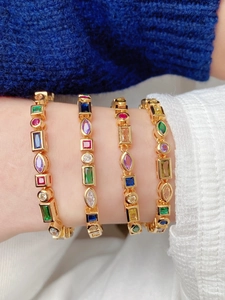 Close-up of gold chain bracelets with colorful zircon stones on model's wrist
