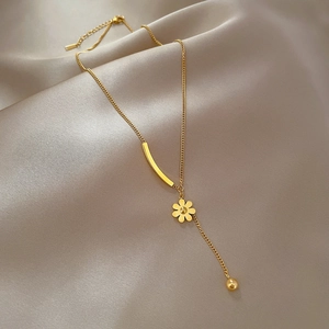 Detailed view of golden flower pendant necklace on beige silk with beaded chain accents