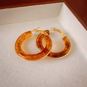 Macro view of amber resin C-shaped earrings with gold metal base in a jewelry box