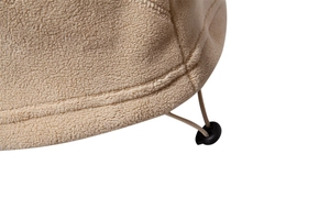 Close-up of beige polar fleece fabric texture with black drawstring buckle and stitching