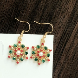Close-up of snowflake earrings with red green crystals and central pearl detail