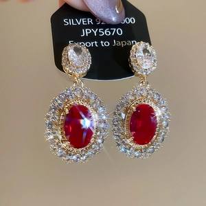 Detail of silver 925 vintage earrings featuring red oval stones and gold plating