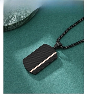 Detail of matte black dog tag pendant with rose gold stripe and ripple texture on green marble