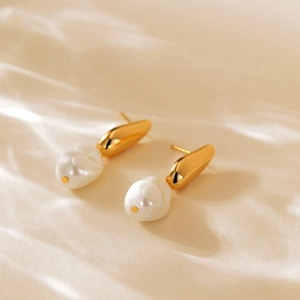 Detailed view of 18K gold plated baroque pearl earrings on soft silk background