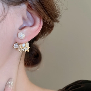 Elegant gold-plated star and flower earrings with faux pearls on model for vintage look