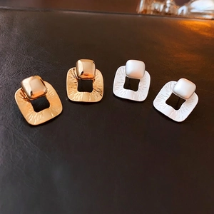 Modern gold and silver plated square stud earrings with radiant texture on black leather