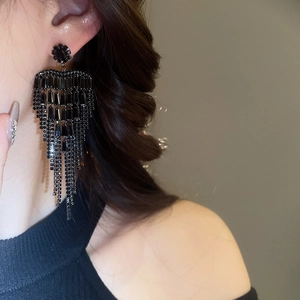 Macro detail of long black tassel earrings with zircon stones worn by a model