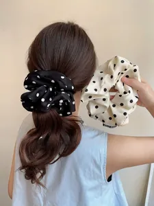 Detailed view of oversized polka dot scrunchies in black and white satin fabric