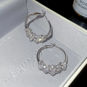 Macro detail of silver-toned twisted hoop earrings with sparkling clustered crystals
