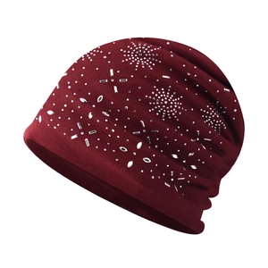 Detail of burgundy knit beanie featuring snowflake rhinestone patterns and soft cotton fabric