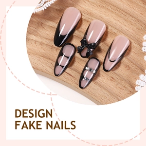 Pink French press-on nails with black bow accents and rhinestones on a wooden background