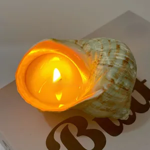 Close-up of a natural shell scented candle glowing with warm orange light inside