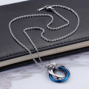 Three interlocking stainless steel rings pendant necklace with crystals on marble background