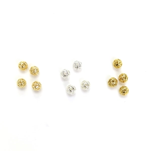 Detalle macro de cuentas redondas huecas de oro de 14k con intrincados motivos florales
