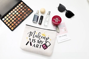 Flat lay of linen makeup bag with cosmetic props, sunglasses and chic letter print
