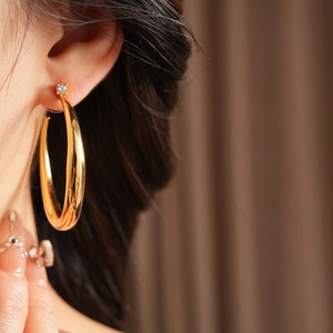 Close-up of elegant gold C-shaped hoop earring with zircon stud worn by a model