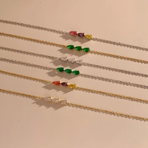 Close-up of elegant gold and silver bracelets with colorful pear-shaped zircon stones
