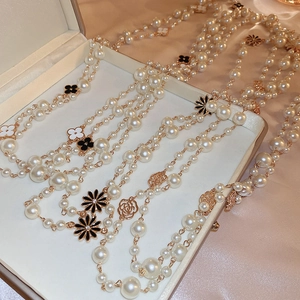 Detail of double-layer pearl necklace with clover and floral charms on pink satin