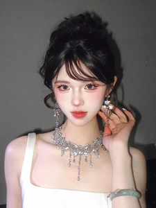 Close-up of silver teardrop diamond necklace and earrings set on an elegant model