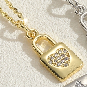 Macro shot of gold padlock pendant featuring heart micro-set zircon and dainty O-chain link