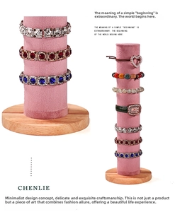 Gros plan d'un présentoir à bijoux en velours rose avec socle rond en bois massif
