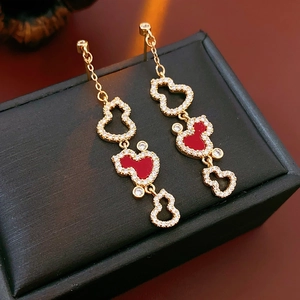 Detail of gold-plated gourd earrings with red enamel and pavé crystals on a jewelry box